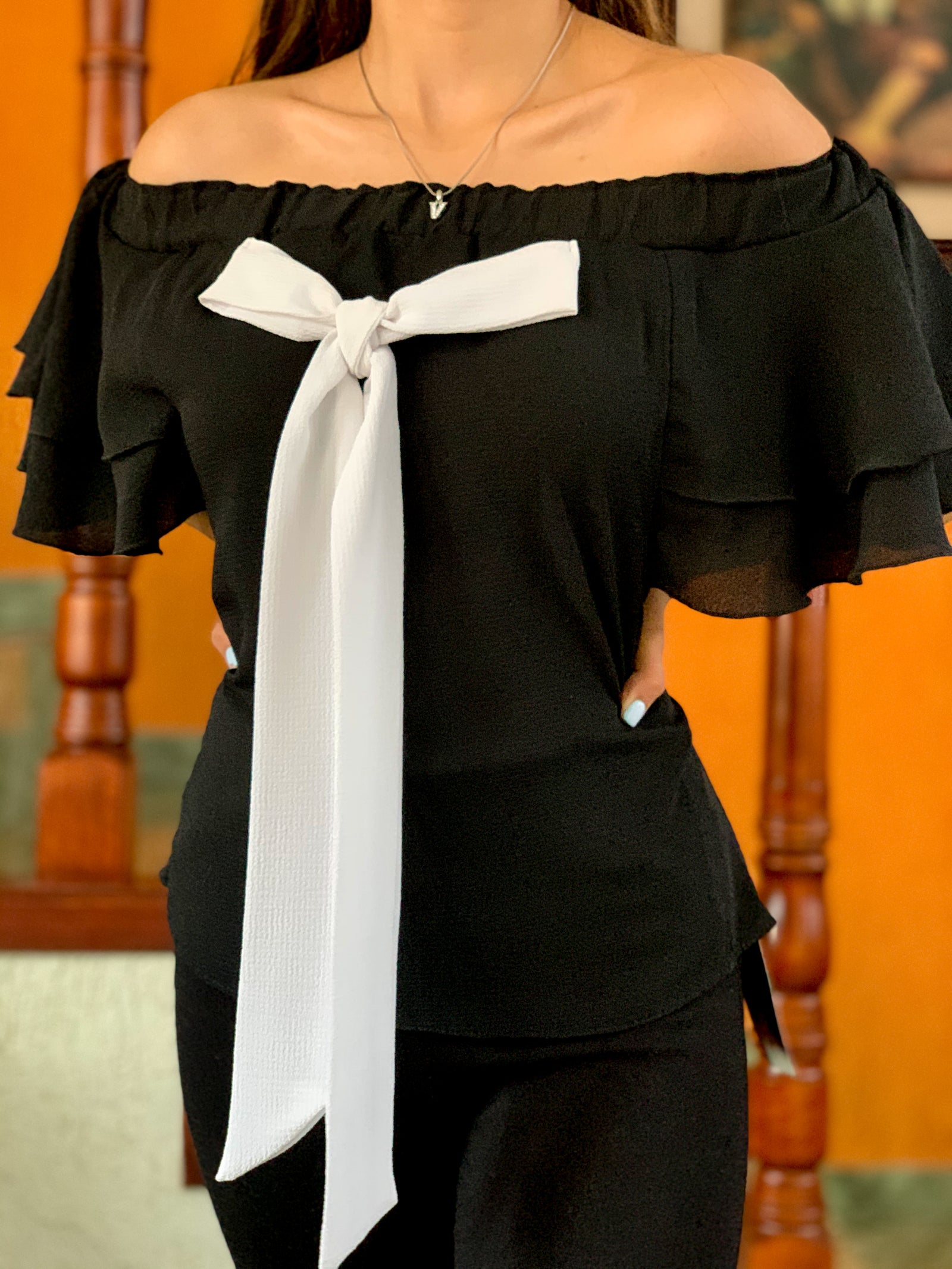 Blusa negra a los hombros con moño blanco al frente