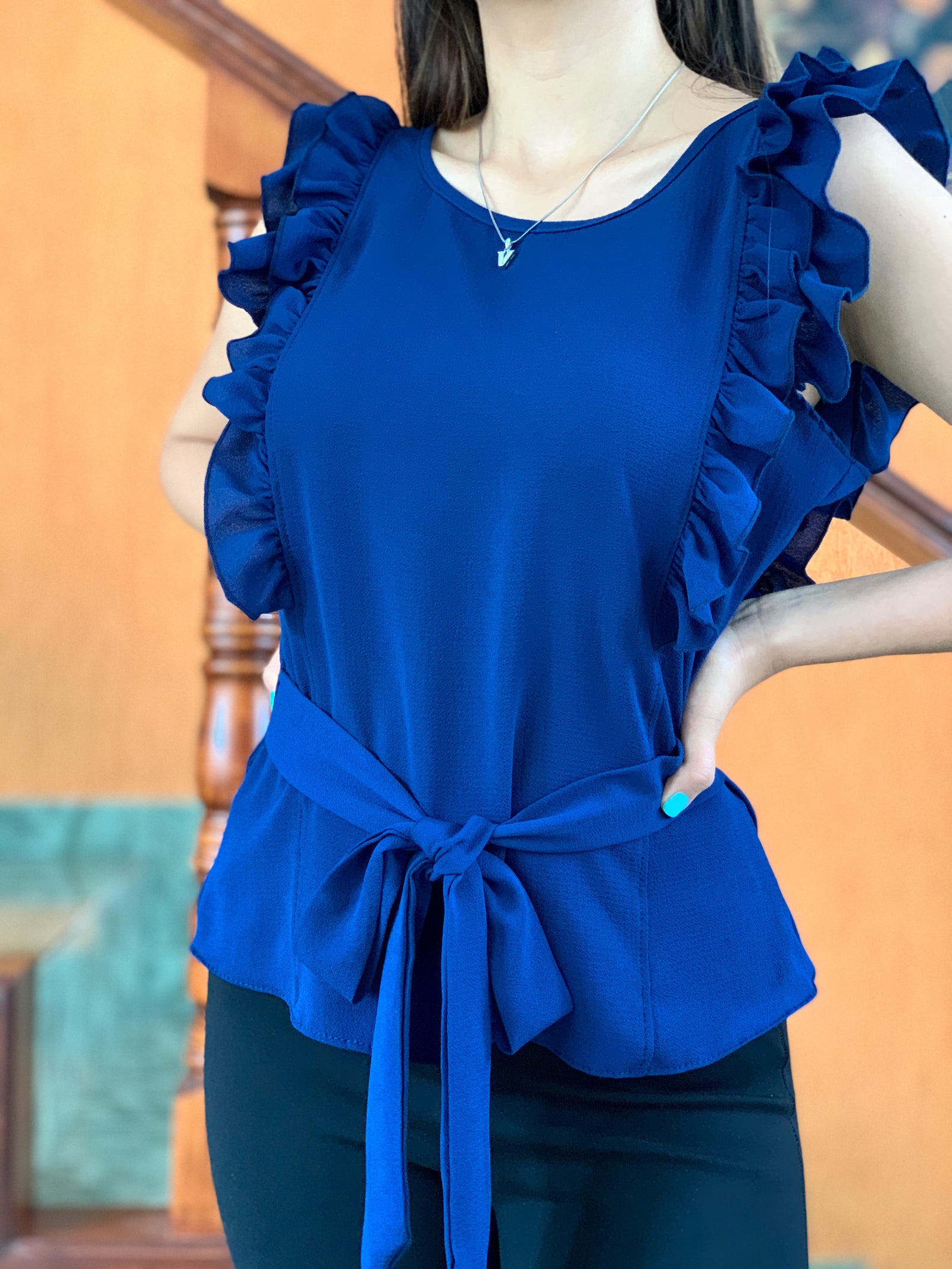 Blusa terminada en festón y cintas para amarrar en la cintura color azul marino.