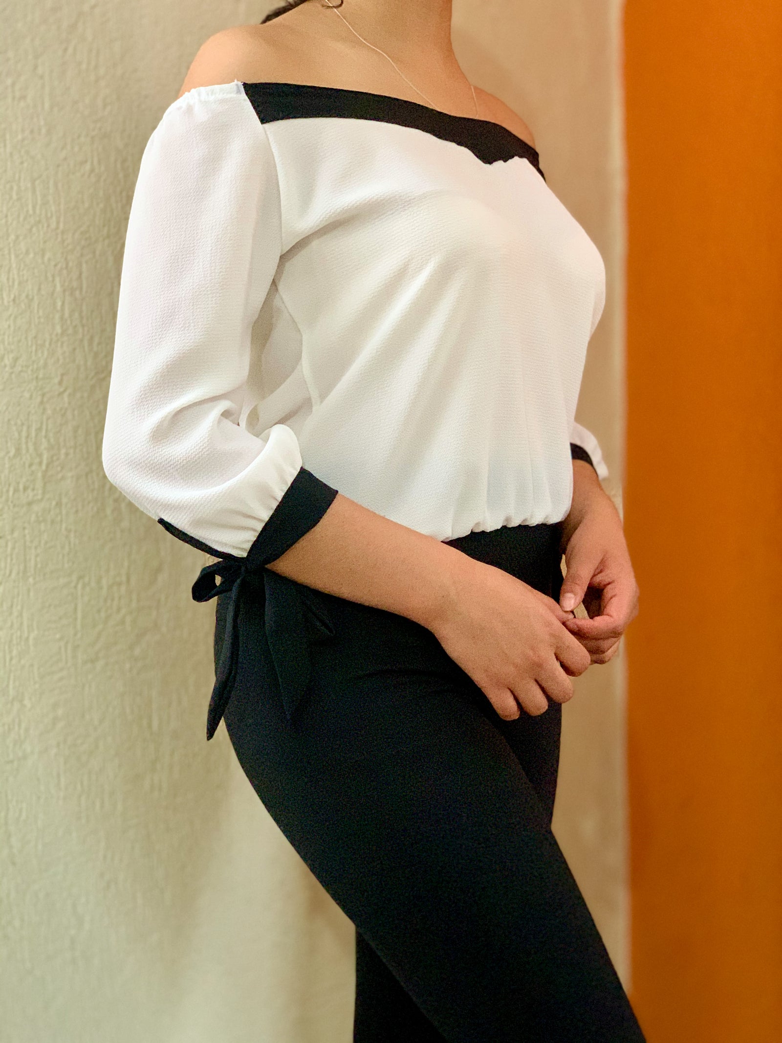 Blusa con cuello en v color blanca y vista negra con cintas en las muñecas.