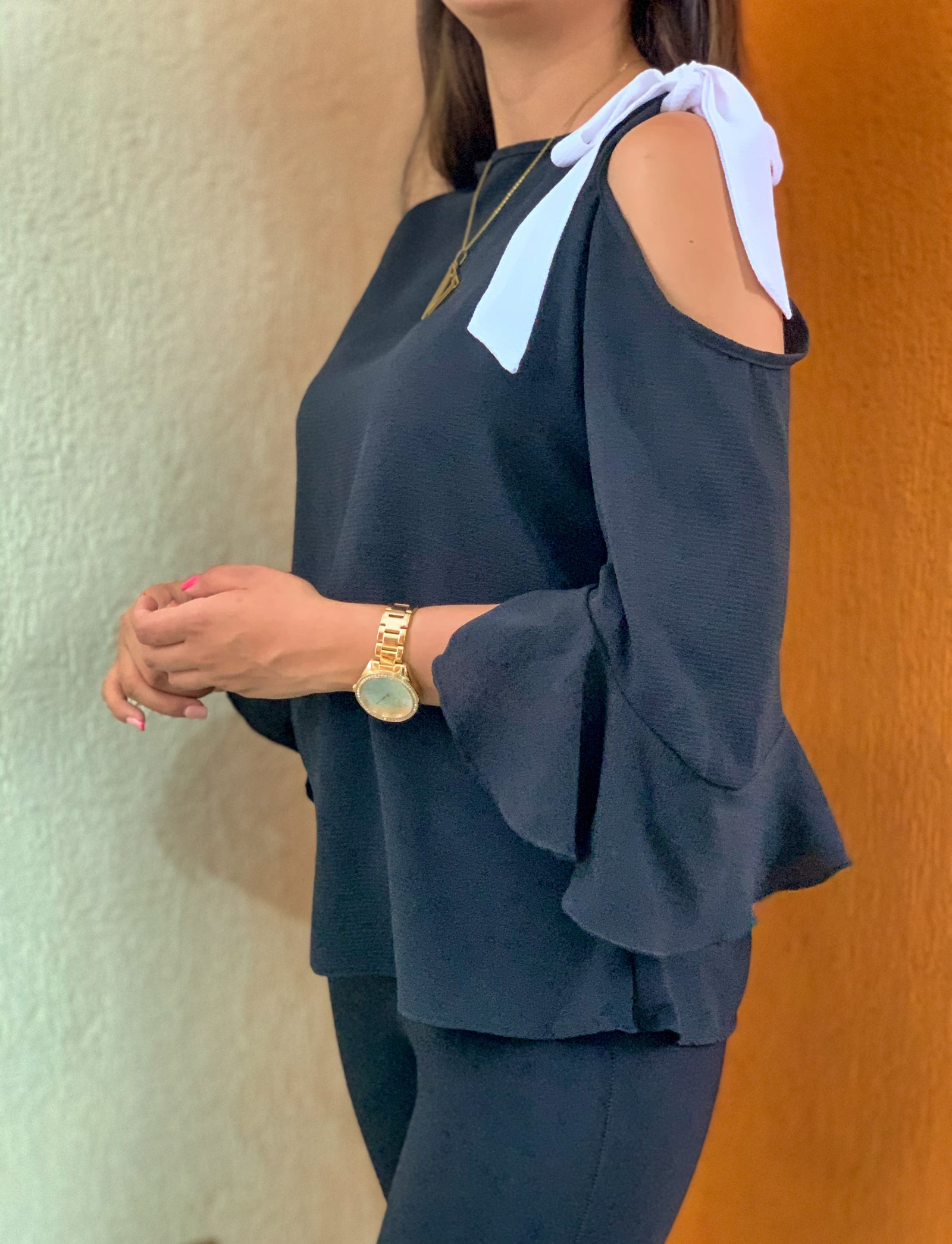 Blusa color negro con manga en campana y tirantes blancos.