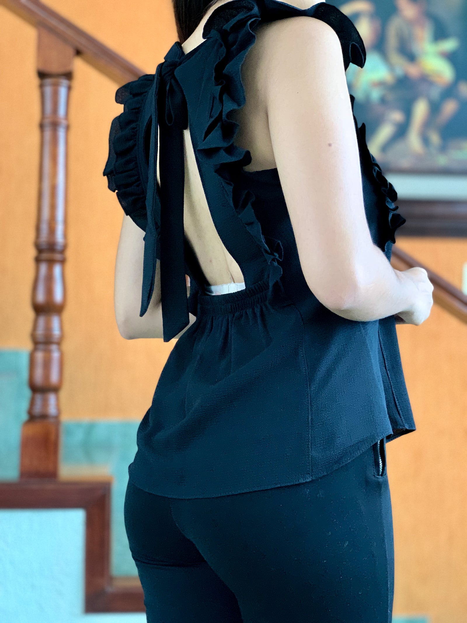 Blusa color negro terminada en festón abierta de atrás.